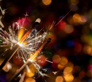 Glowing holiday sparkling hand fireworks shining fire flame christmas light abstract background e1714234839759 360x320